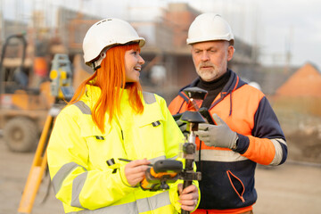 Male and female builders collaborate on-site, discussing project details while surveying at building site