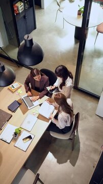Team of Asian women working on laptops in industrial-style home office with collaborative and focused energy