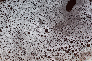 A close-up view of foam bubbles of varying sizes, creating an abstract texture