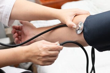 Measuring Blood Pressure: A healthcare provider taking patient's vitals using a stethoscope and...