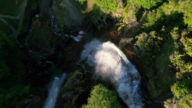 Acquafraggia waterfalls cascading into pool with misty spray, Lush green surroundings, Val Bregaglia, Lombardy, Italy. Aerial top-down pov