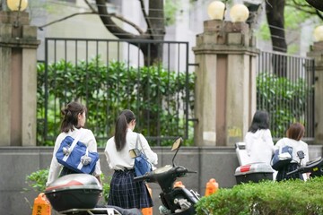 In early June in Pudong, Shanghai, seven Japanese high school girls in summer uniforms walk...