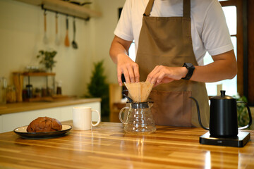 Hands of a person making fresh coffee with a manual brewing method in a kitchen