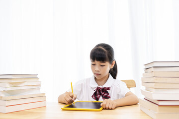 A Chinese little girl is drawing on a drawing board