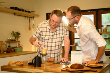 Senior man and son brewing fresh coffee together during a cozy morning at home. Father day concept