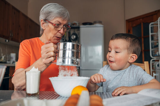 Grandmother and grandson preparing dough in kitchen