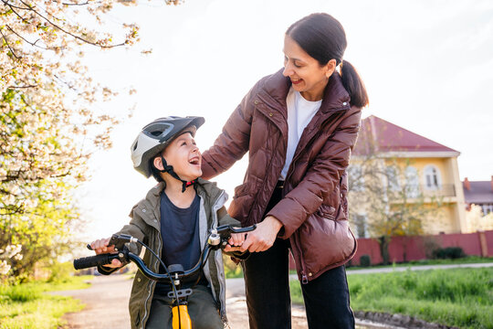 Mother teaching son to ride a bicycle outdoors in a fun and supportive environment