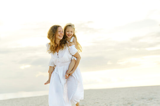 Happy mother giving piggyback ride to daughter at beach