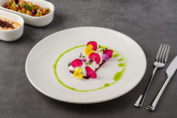 Colorful beetroot slices with goat cheese, garnished with edible flowers