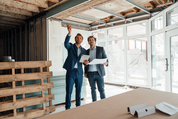 Two men in business attire discussing energy efficiency at a construction site