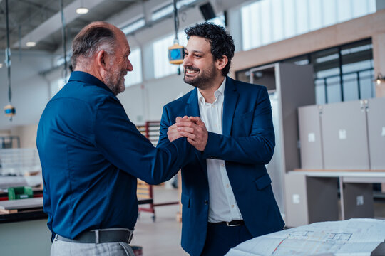 Engineers shaking hands in an office, symbolizing trust and collaboration - Powered by Adobe