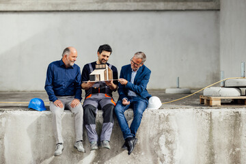 Engineer and craftsmen discussing a model outdoors