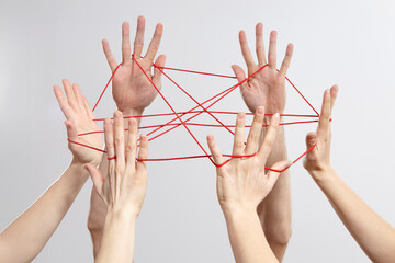 Hands connected by red string symbolizing teamwork and networking