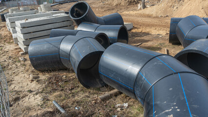 Construction site featuring various diameters of polyethylene pipes for water supply. Durable and...