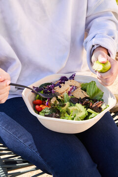 Woman eatting a to go salad outside