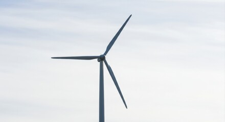 Fototapeta premium Clean energy wind turbine blades against a soft sky.