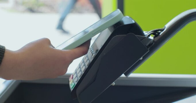Woman paying with smartphone at the checkout counter in the supermarket. Payment scanning nfc technology contactless payment wireless device concept.
