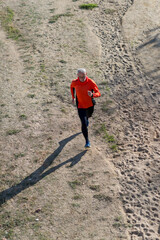 Senior man running on dirt trail from aerial perspective