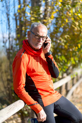 Senior man in sportswear talking on phone outdoors
