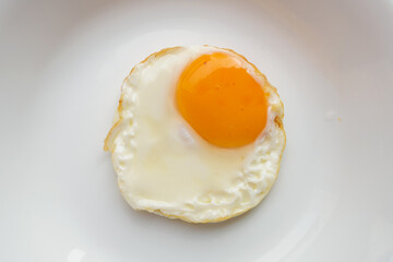 Fried egg on white dish close up