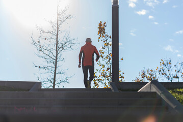 Active senior man climbing stairs in outdoor park sunlight