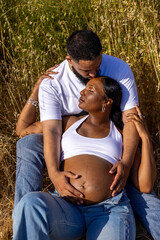 An extremely joyful African American couple joyfully enjoys a beautiful sunny day outdoors, celebrating their wonderful pregnancy with warmth, love, and a sense of anticipation and happiness