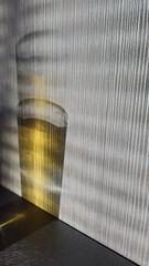 Reflection of a juice glass on a grey striped kitchen wall