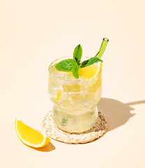 Fresh mocktail mojito with lemon, mint and ice. Citrus lemonade on a yellow background.