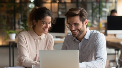 Professional teamwork in office: two young colleagues working together on laptop, talking about financial project management, business goals, and corporate tasks in modern environment