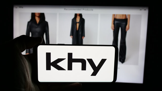 Stuttgart, Germany - 05-25-2025: Person holding cellphone with logo of US fashion company K Brand Inc. (Khy) on screen in front of webpage. Focus on phone display.