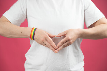 Woman with wedding ring and rainbow bracelet showing heart sign. 