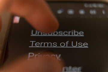Finger tapping on a smartphone screen with visible Terms of Use links in dark mode.