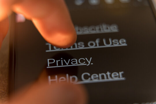 Close-up of a finger tapping the Privacy link on a smartphone screen in dark mode interface.