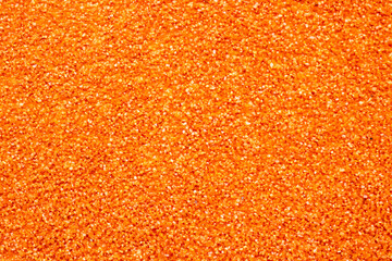 Here is a detailed close up image of a vibrant pile of orange glitter