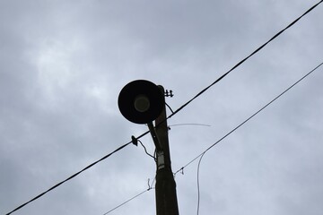 Streetlight silhouette against a cloudy sky with visible power lines