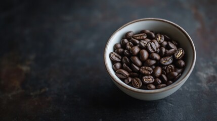Fototapeta premium Coffee beans in ceramic bowl on dark stone surface with dramatic rustic morning light