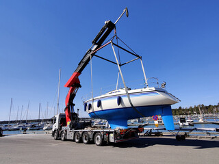A sailboat is being lifted by a crane in a harbor in Suomenoja, Espoo, Finland. The vessel...