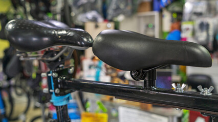 Closeup Of A Sleek Black Leather Bicycle Saddle In A Vibrant Sports Equipment Store. Detailed View Of A Black Bicycle Seat With Metal Hardware On Display In A Retail Shop.