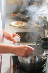Young woman working remotely from the kitchen, balancing cooking and video call, enjoying mindful morning routine and modern lifestyle. Home office, wellness, healthy habits.