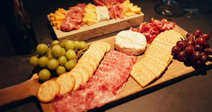 Cheese board, cold meat and grapes with crackers for snack, food or charcuterie for catering. Healthy, fruit and gourmet selection with fresh ingredients on wooden surface for nutrition or meal