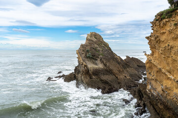 Rocky formation in the Atlantic Ocean with visible erosion patterns and waves crashing