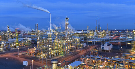 refinery - chemical factory at night with buildings, pipelines and lighting - industrial plant