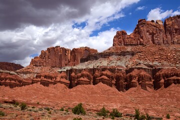 colorful eroded red rock formations and ominous storm clouds on a sunny summer day in capitol reef national park, near torrey, utah