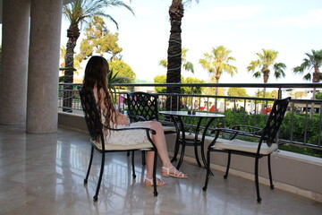 a girl on vacation sits at a table, admiring the beautiful views around and enjoying the moments in...