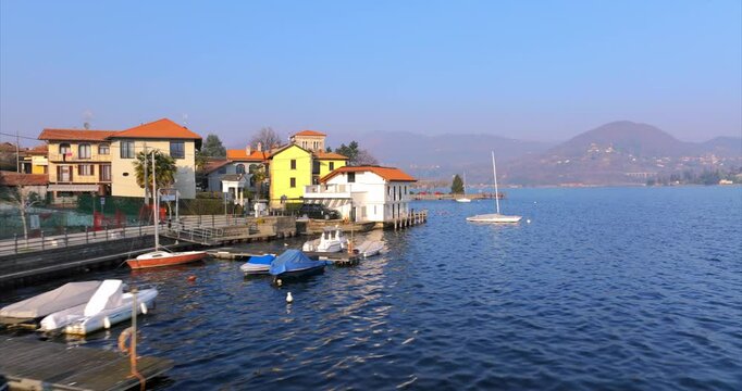 Low aerial flying along picturesque waterfront town of Pella, Italy on Lake Orta