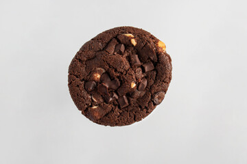 A large chocolate cookie topped with chocolate chips, set against a white background.