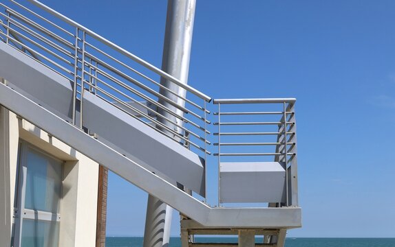 Modern outdoor metallic staircase with sky and sea on background.