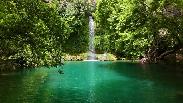 Kursunlu Waterfall cascading into a vibrant turquoise pond, surrounded by lush greenery in Antalya, Turkiye