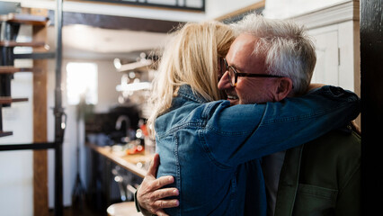 Senior couple embracing happily in their kitchen at home