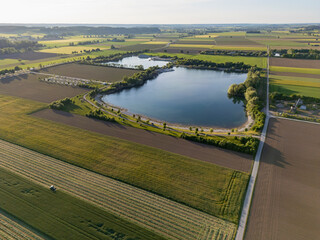 Landscape drone view of rural Bavaria with fields and a beautiful blue lake at sunset